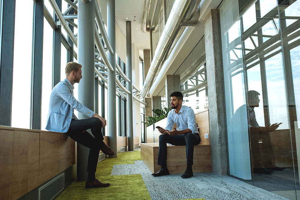 Two colleagues having a casual chat in the office lobby.